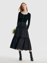 One lady wears a black top and a denim maxi skirt.